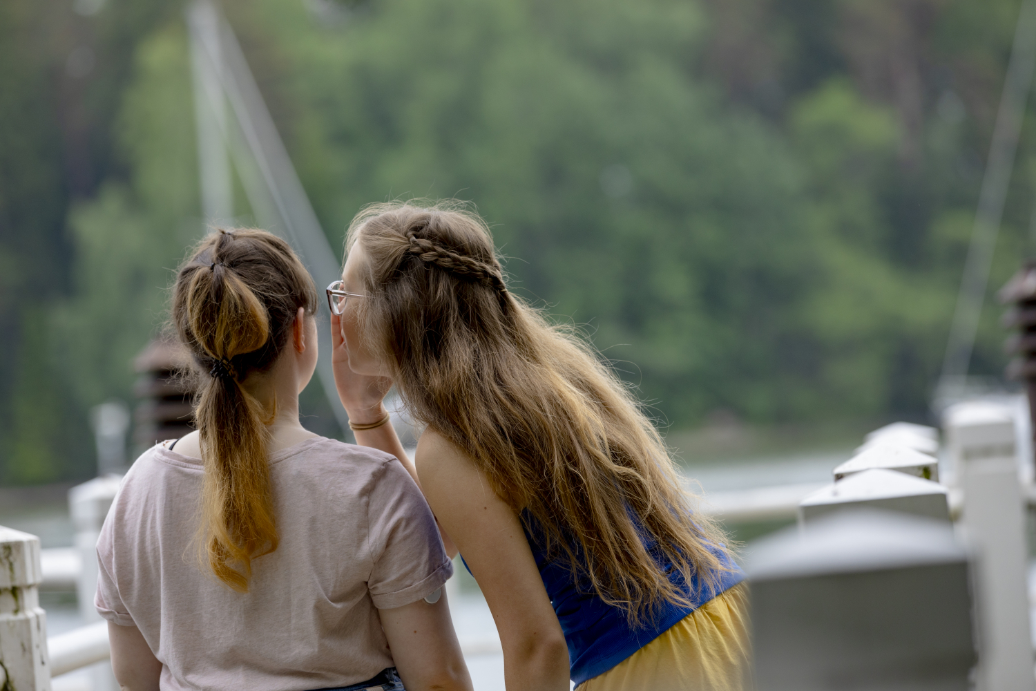 Kaksi nuorta kuiskuttelee sillalla.